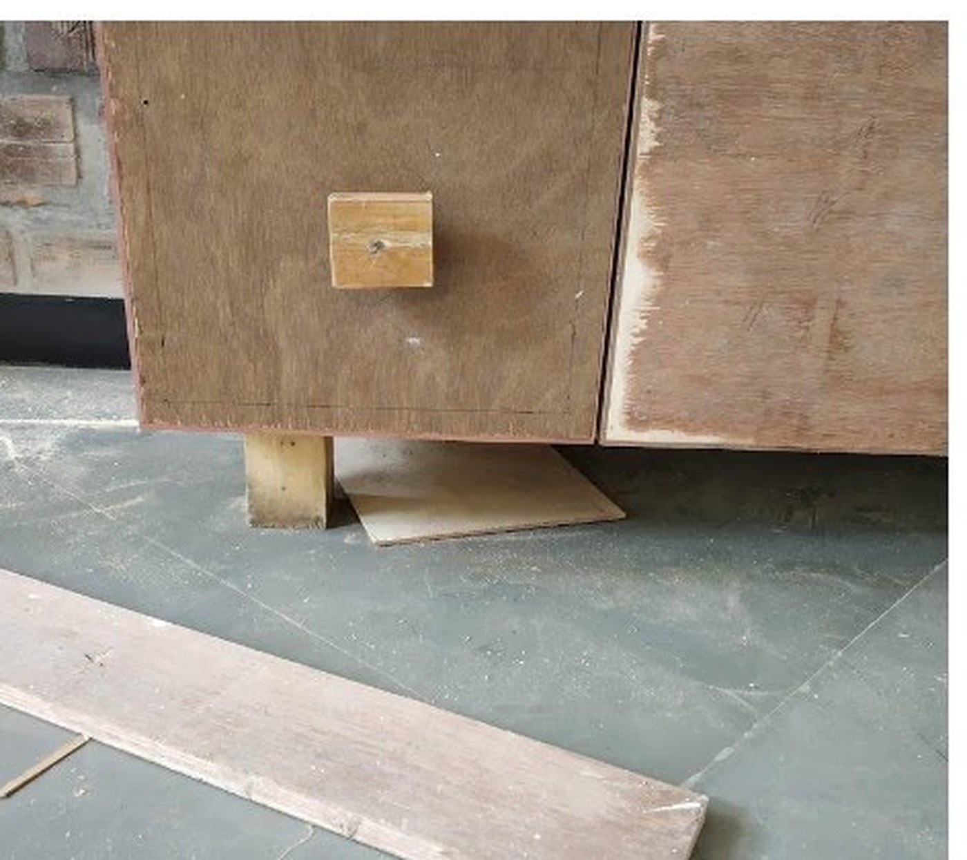 The console stripped back to bare plywood, mid restoration on a workshop floor