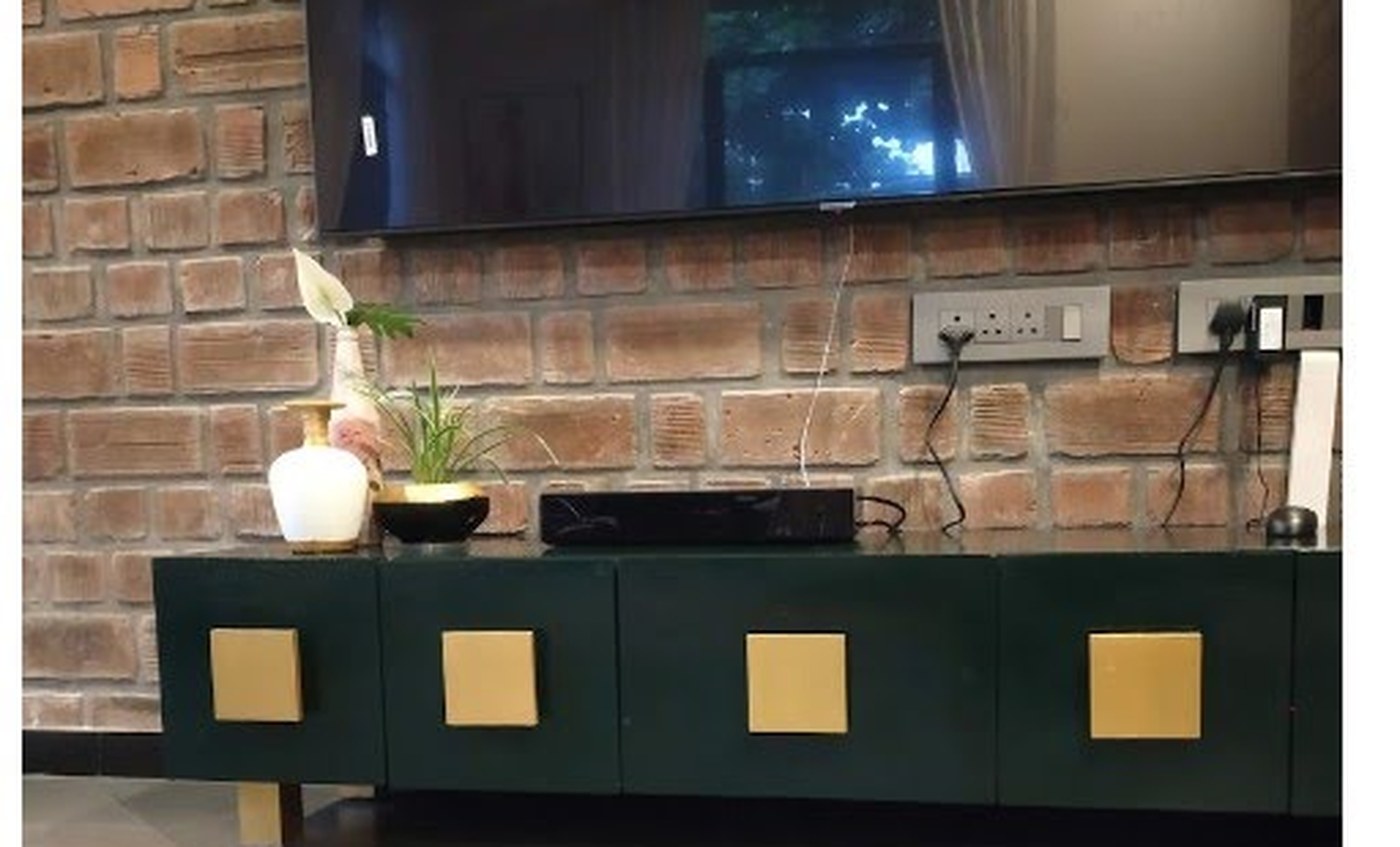 The finished console, repainted deep green with brass panels, against a brick wall